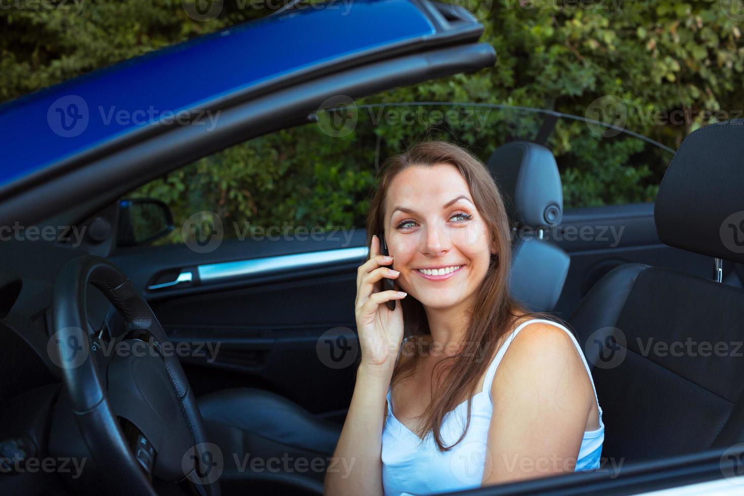 Smiling woman talking on phone in a cabriolet car photo