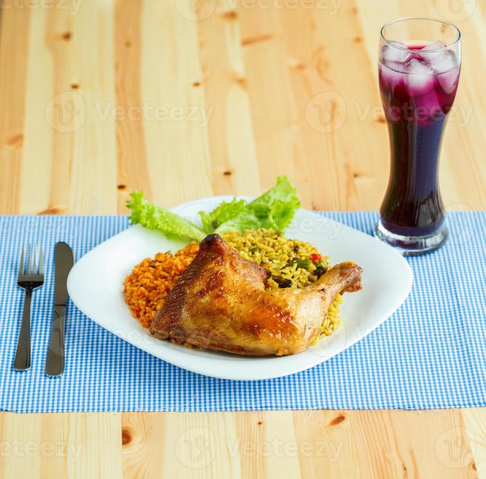 platos desde pollo muslo con arroz y lechuga y un vaso de jugo con hielo foto