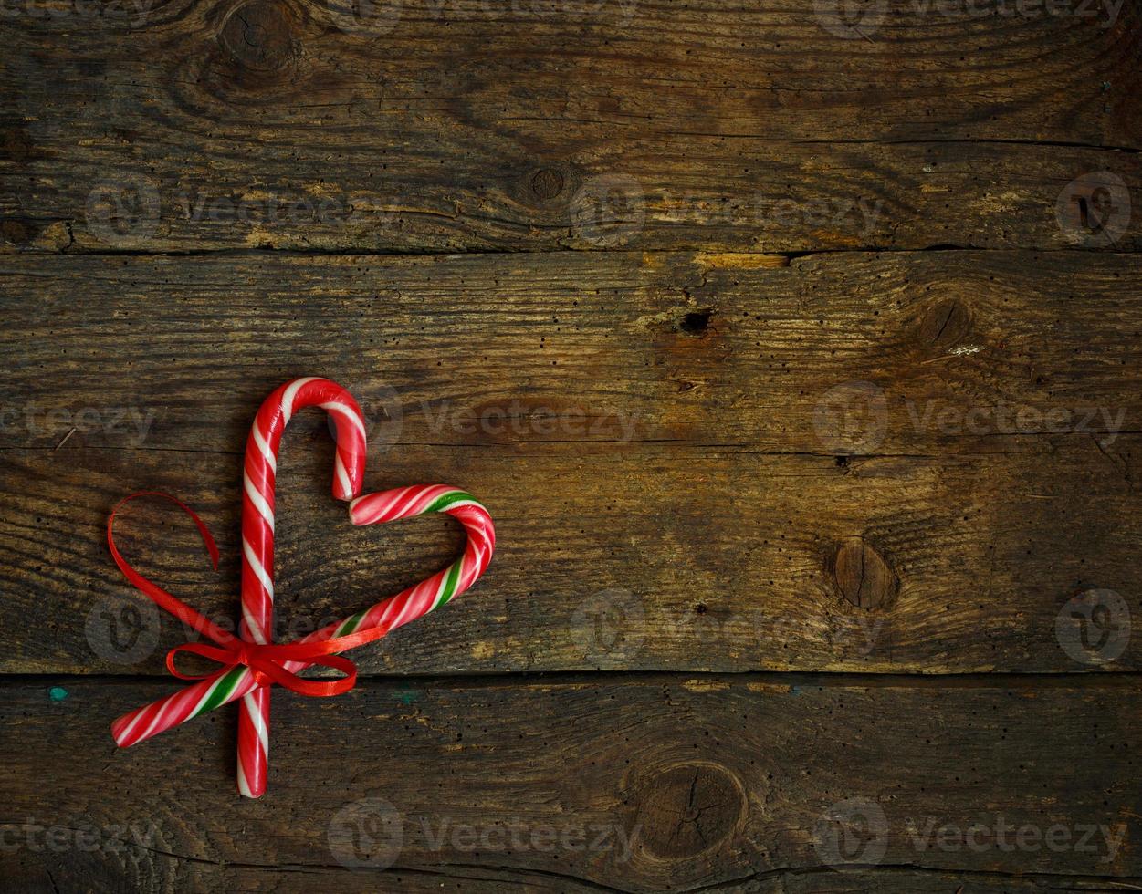 Candy canes in the heart shape on a wooden background photo
