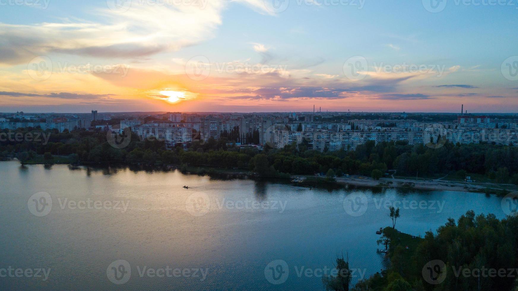 volador terminado el arboles y lago en el ciudad a amanecer - aéreo foto