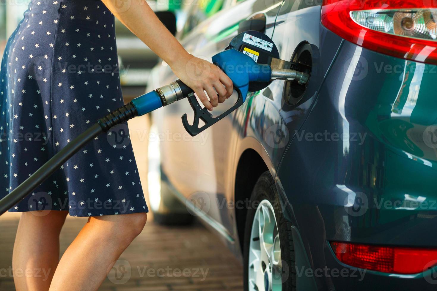 Woman fills petrol into the car at a gas station photo