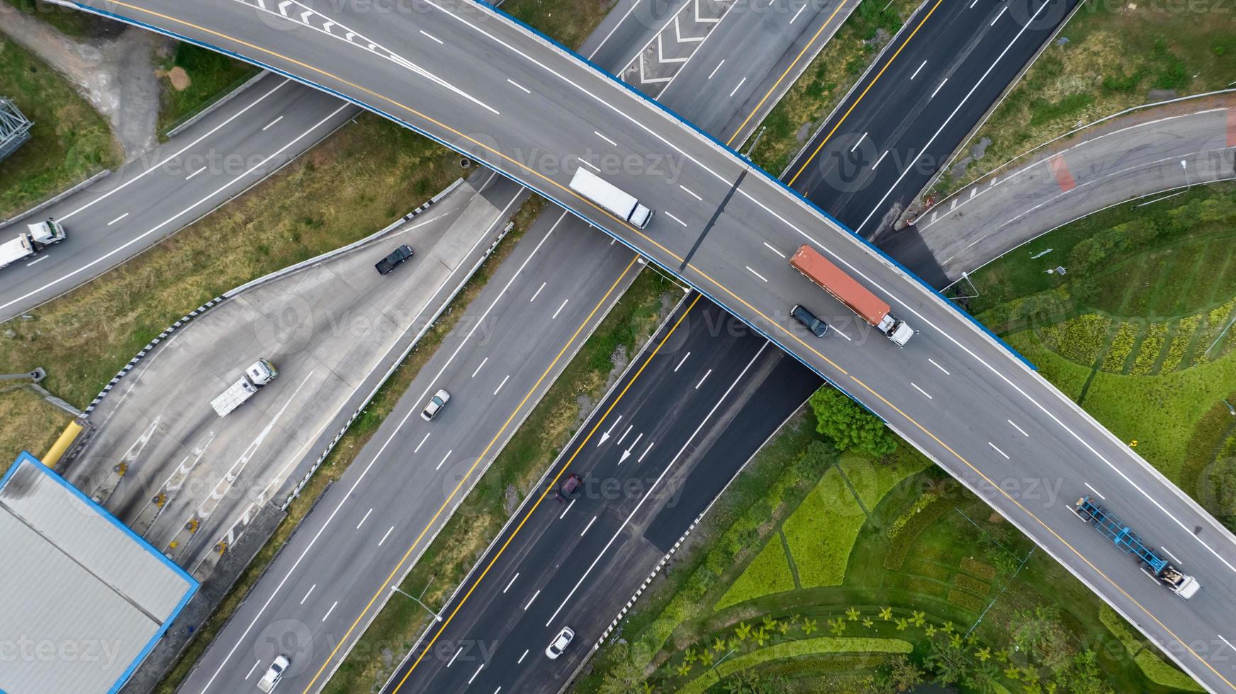 Aerial top view of highway junction interchange road. Drone view of the elevated road, traffic junctions, and green garden. Transport trucks and cars driving on highway. Infrastructure in modern city. photo