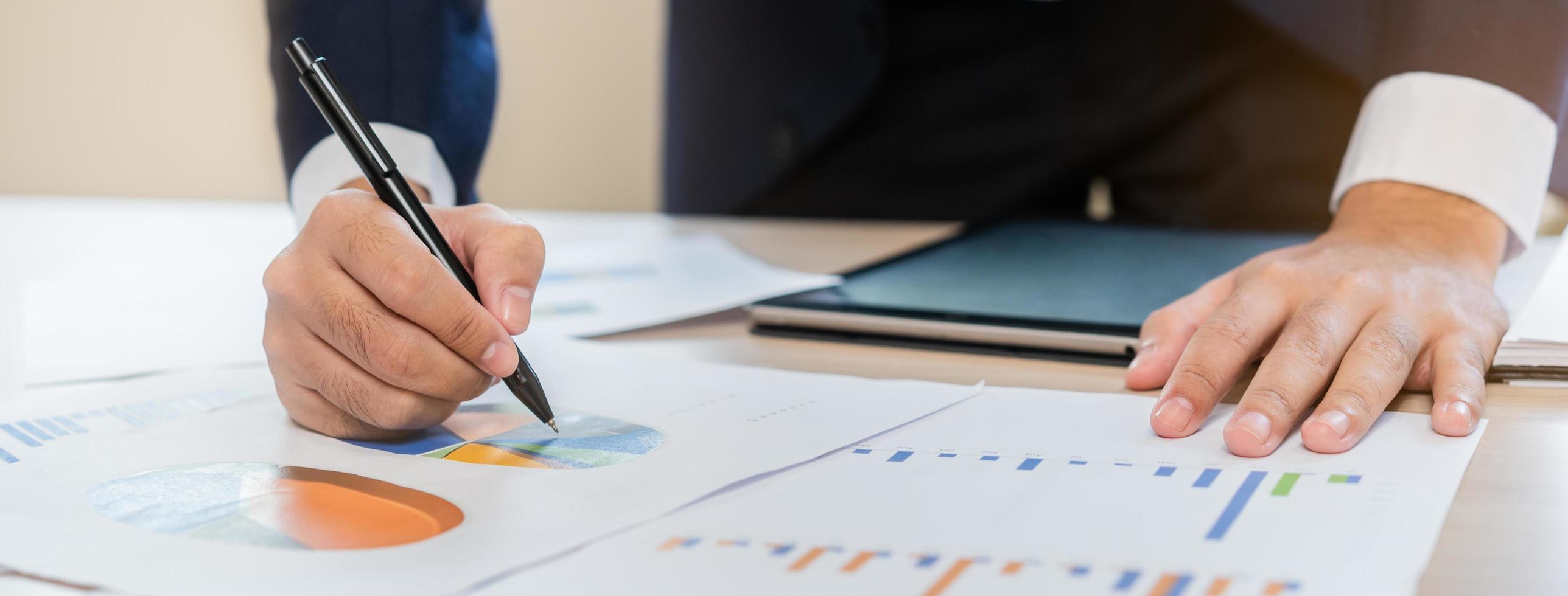 Business meeting, asian businessman brainstorm, analyzing graph data of cost plan, discussing in board room, using touchpad on desk. People working conference room. photo