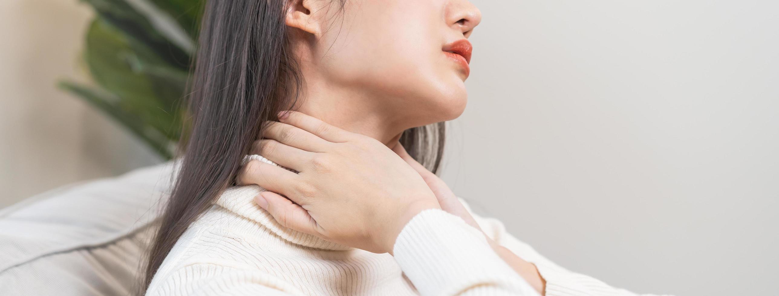 Body muscles stiff problem, asian young attractive woman, girl pain with neck pain ache from work, holding massaging rubbing shoulder hurt or sore, painful sitting on sofa at home. Healthcare people. photo