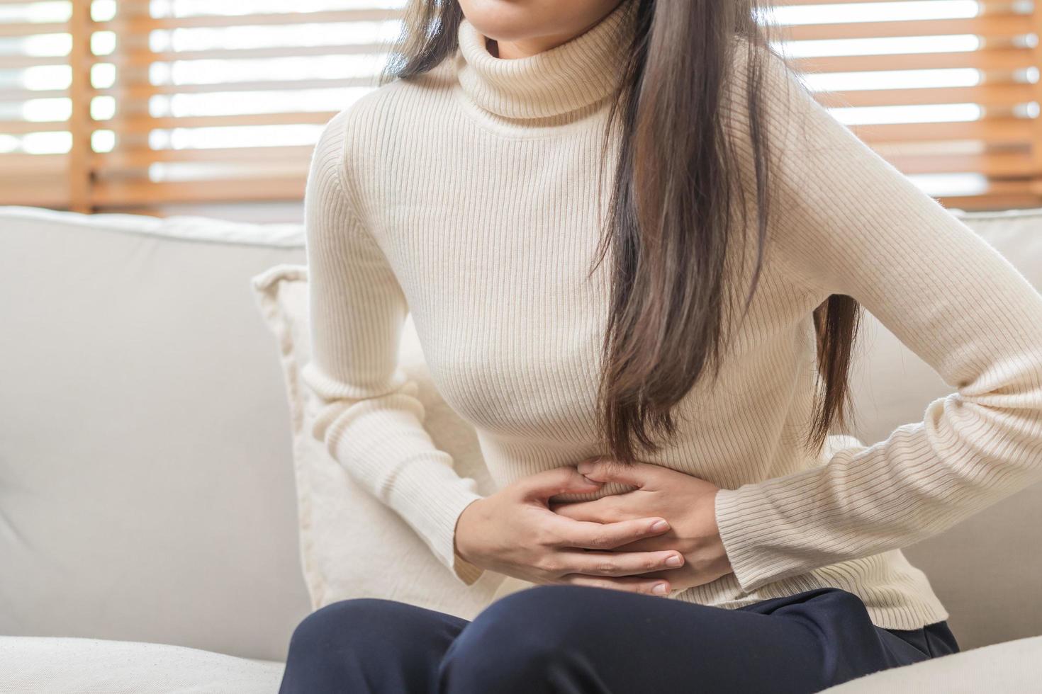 Flatulence asian young woman, girl hand in stomach ache, suffer from food poisoning, abdominal pain and colon problem, gastritis or diarrhoea. Patient belly, abdomen or inflammation, concept. photo