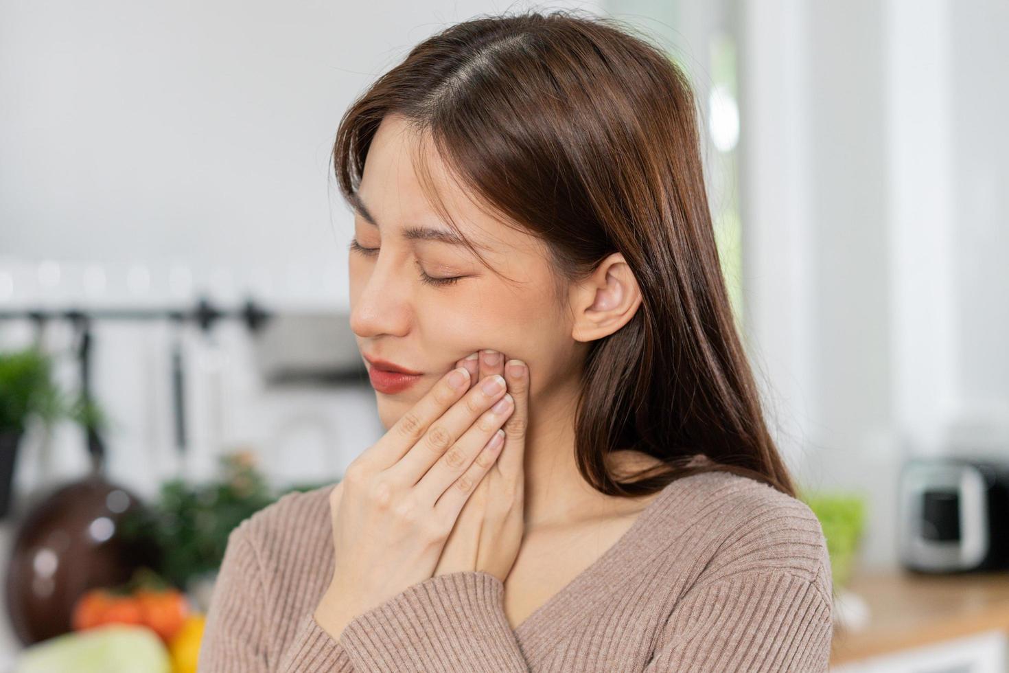 Closing eyes asian young woman touching cheek, face expression from toothache, tooth decay or sensitivity, Having tooth or teeth problem or inflammation, suffering from health. Sensitive teeth people photo