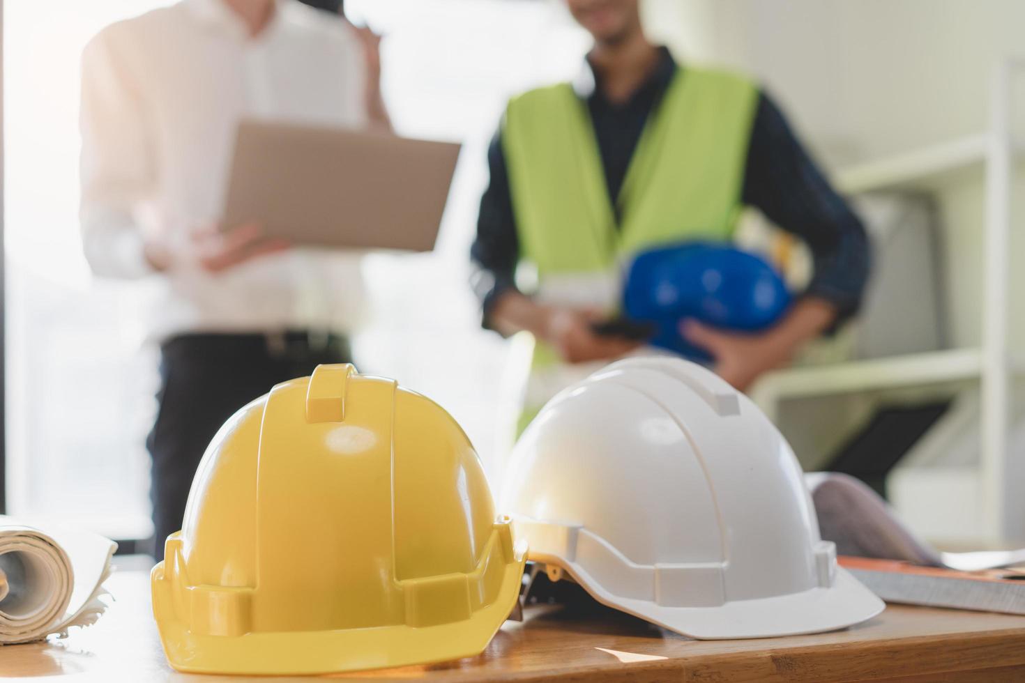 Close up white, yellow safety helmet. Asian, caucasian young engineer, architect two man are discussing construction to follow the project to build an industrial plan at site. Engineer worker people. photo