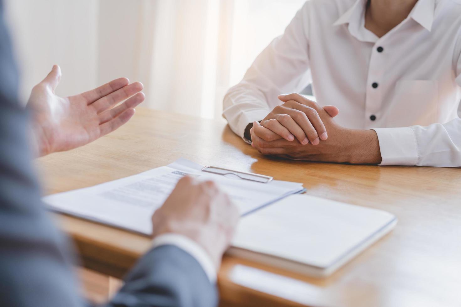 asiático joven gerente, empleador hombre entrevista con persona, tener pregunta acerca de currículum y escucha a candidato respuesta, conversacion juntos a oficina. reclutamiento empleado trabajo concepto. foto