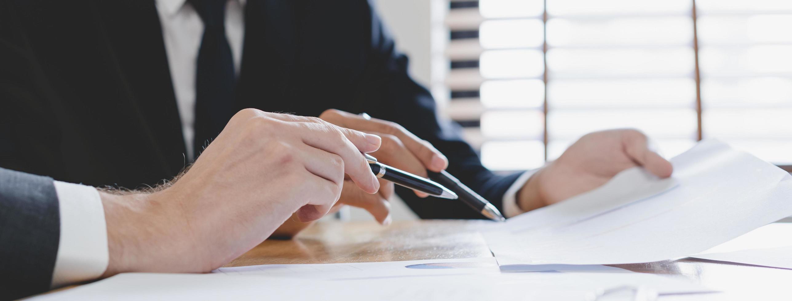 Business meeting, two caucasian, asian group man use pen, brainstorm analyzing on graph data of cost plan or document, paperwork and discussing in board room on table. People working conference room. photo