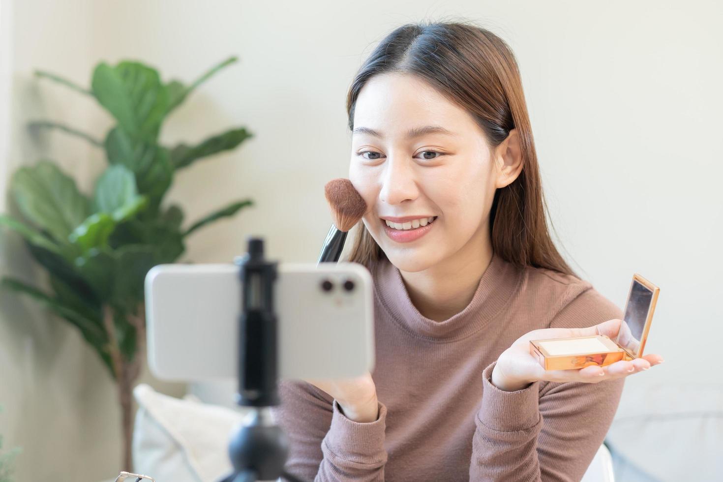 Beauty blogger, asian young woman, girl vlogger makeup face, showing, reviews cosmetics products while recording video, tutorial to share on social media. Business online influencer on smartphone. photo