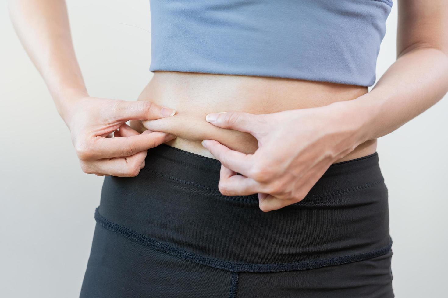 obeso, obesidad, gordito adolescente asiático joven mujer, niña mano en participación barriga, espectáculo exceso grasa de cintura, barriga. forma arriba sano estómago músculo, ganancia perder peso y exceso de peso graso. dieta personas concepto. foto