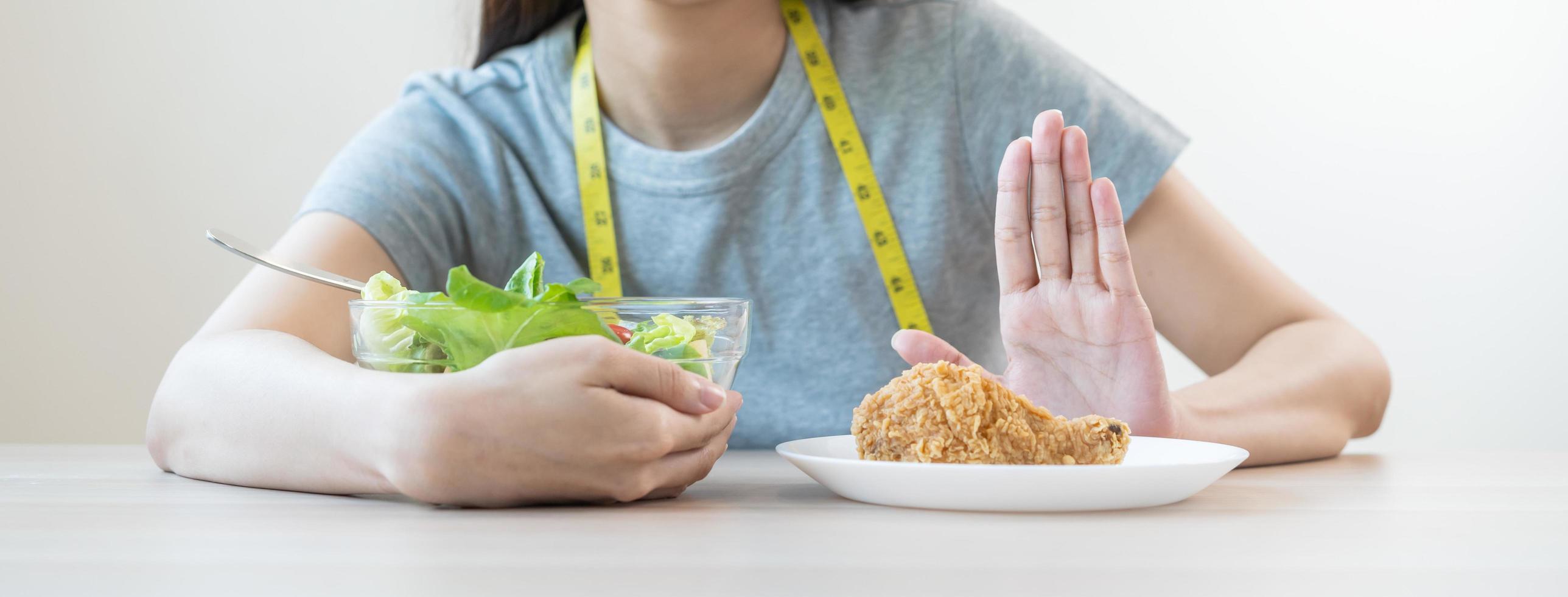 dieta, dieta asiático joven mujer mano en empujar afuera, negar frito pollo, basura comida y escoger Fresco vegetales ensalada de bol, comer comida para bueno saludable, salud cuando hambriento. hembra peso pérdida gente. foto