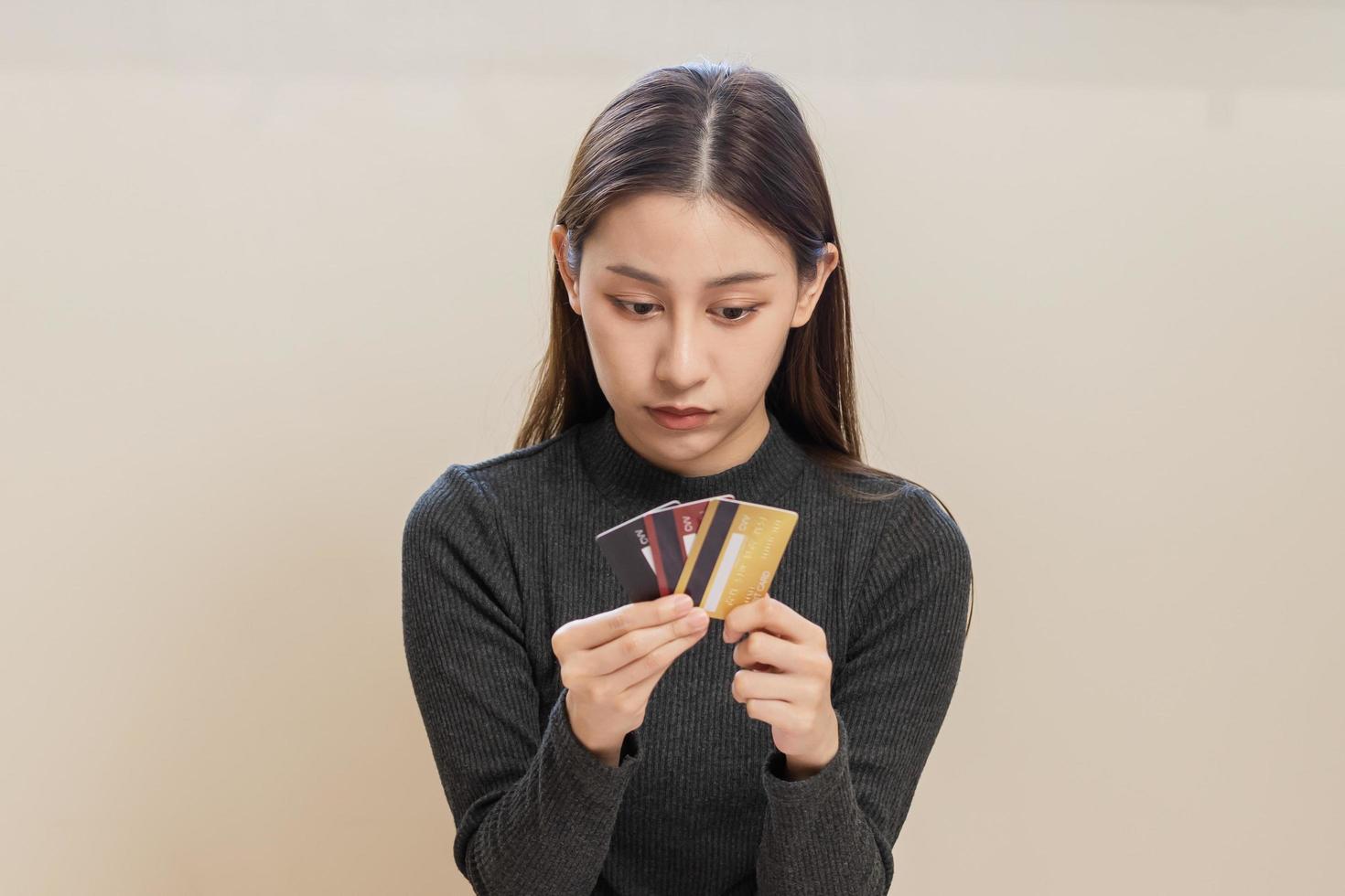 financiero deber, mano de asiático mujer, niña mano en tenencia, mirando a muchos crédito tarjeta, estresado por calcular gastos desde factura, No dinero a pagar, hipoteca o préstamo. deuda, bancarrota o arruinado. foto