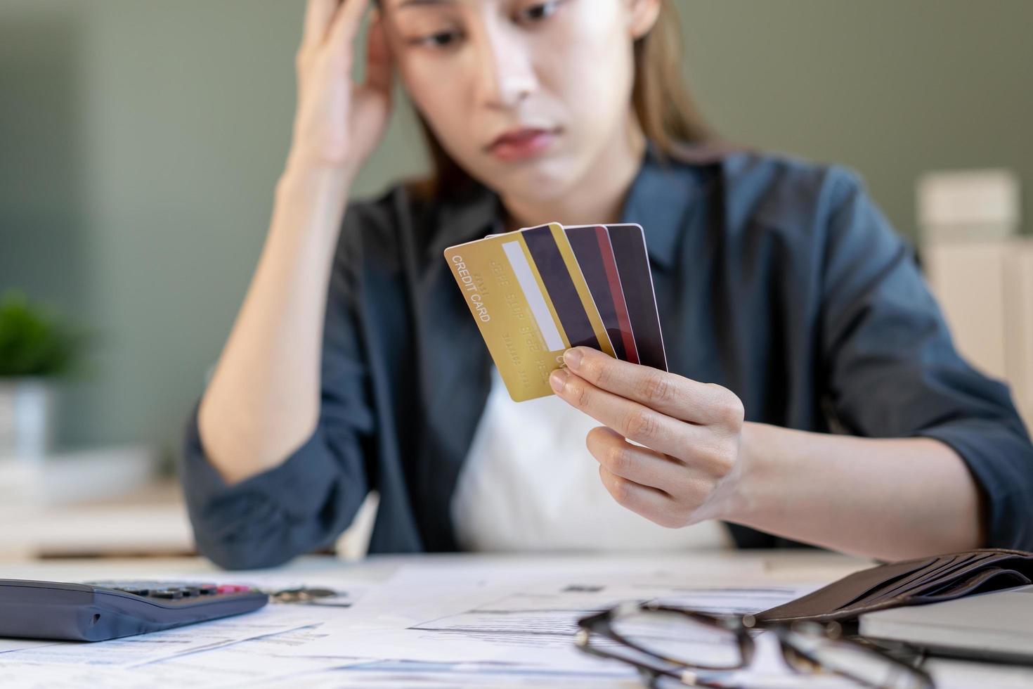 Financial owe, hand of asian woman sitting, holding many credit card, stressed  by calculate expense from invoice or bill, no money to pay, mortgage or loan. Debt, bankruptcy or bankrupt photo