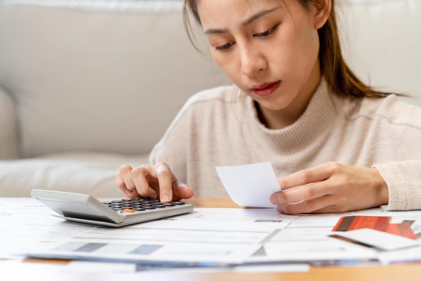 Financial owe asian young woman, girl sitting suffer, stressed and confused by calculate expense from invoice or bill, have no money to pay, mortgage or loan. Debt, bankruptcy or bankruptcy concept. photo