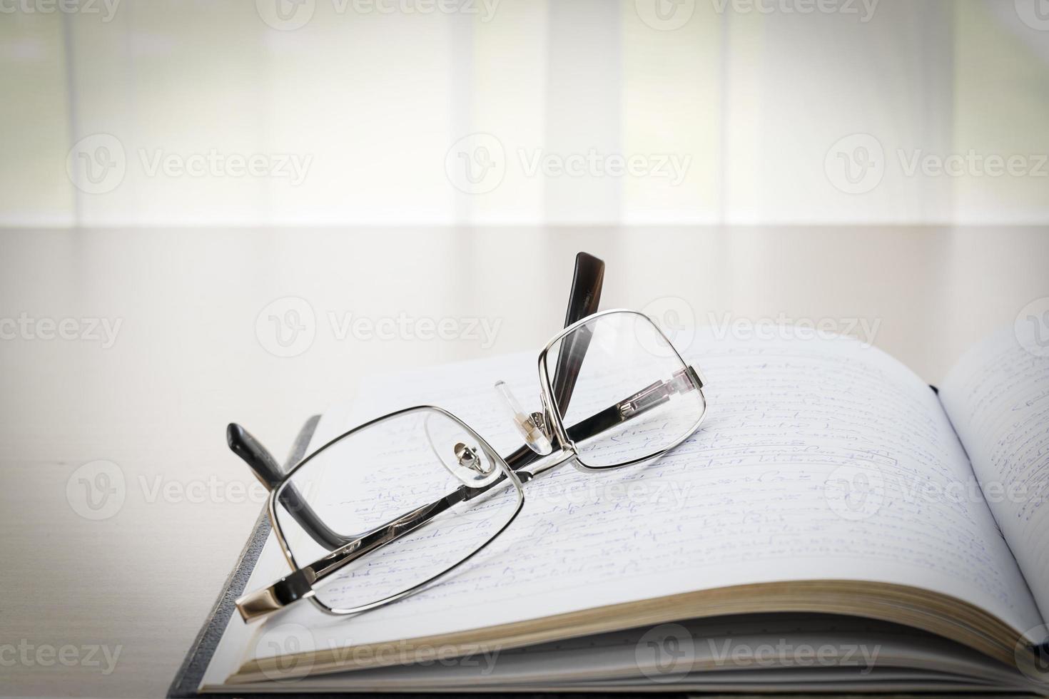 Eyeglasses put on a book with on the desk photo
