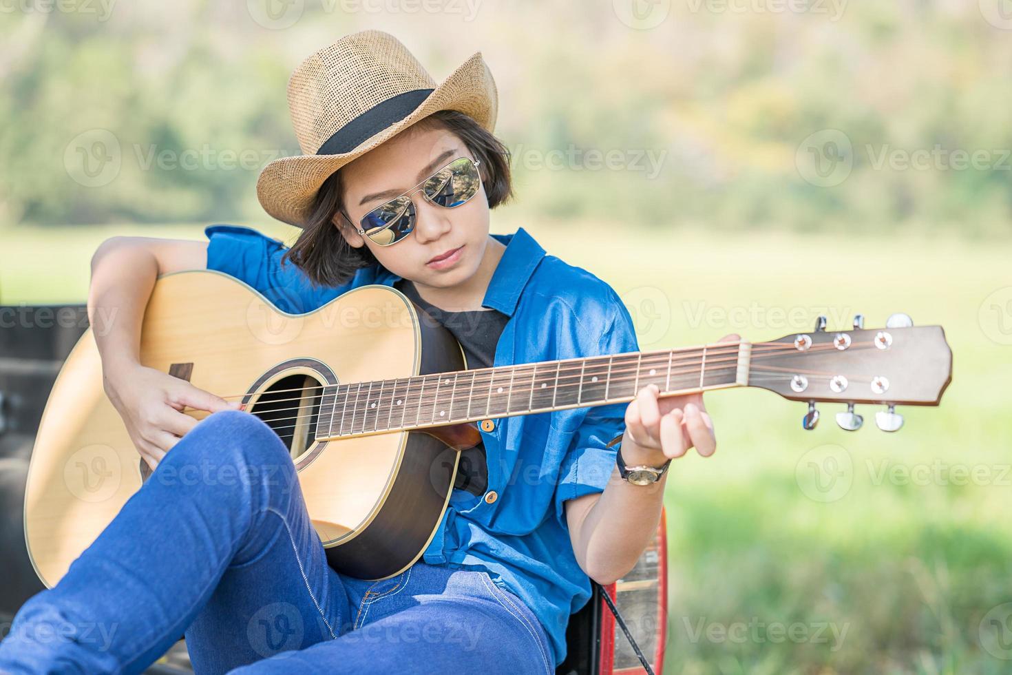 Woman wear hat and playing guitar on pickup truck photo