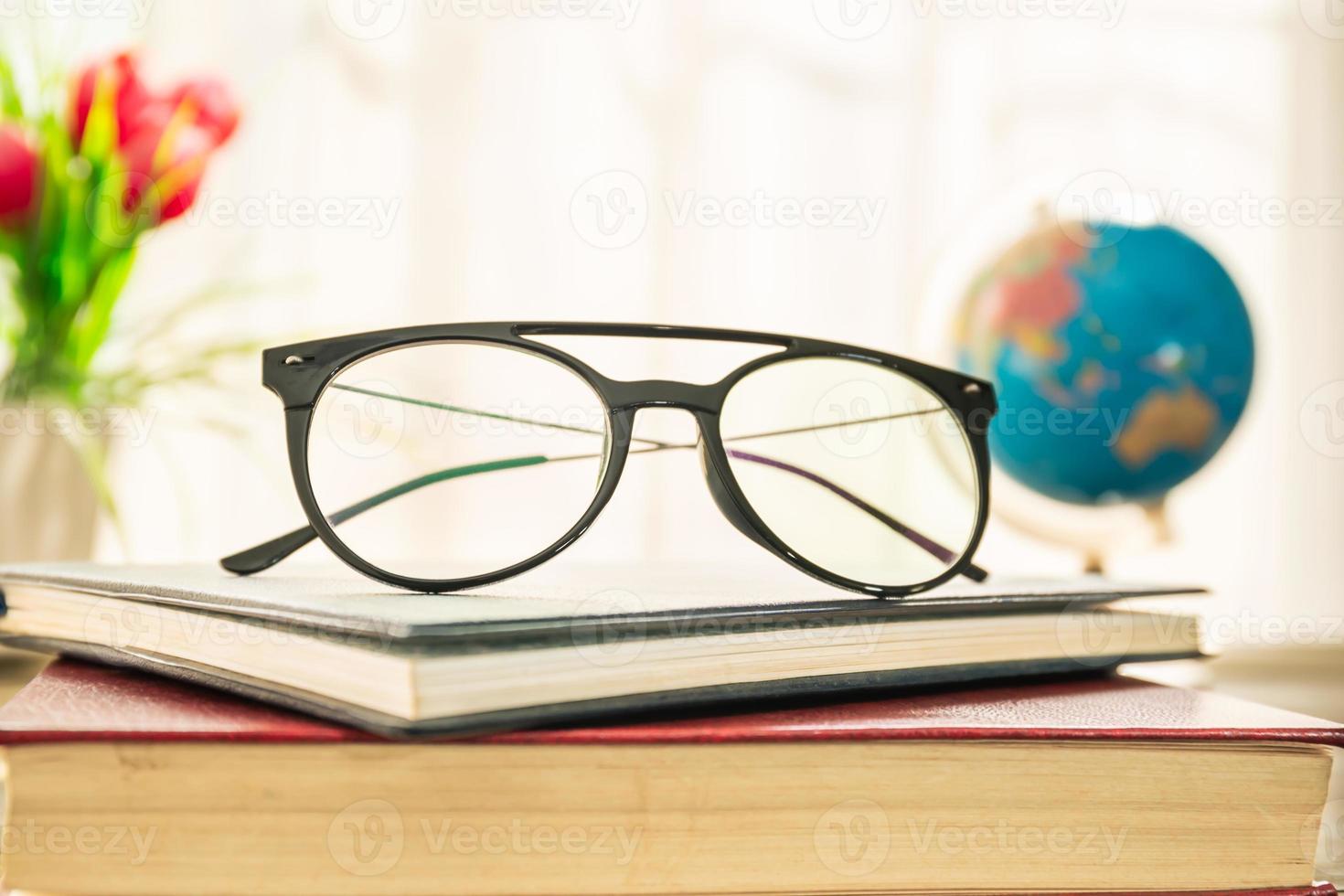 Reading glasses put on hardcover book beside the window photo