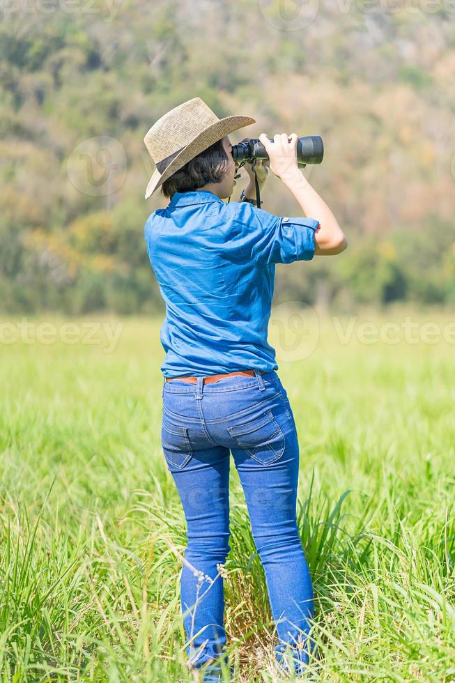 Woman wear hat and hold binocular in grass field photo