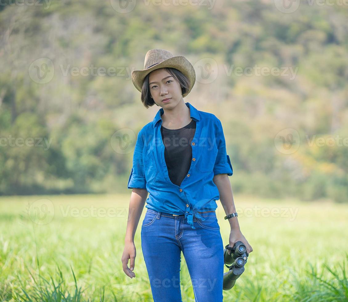 mujer use sombrero y sostenga binocular en el campo de hierba foto