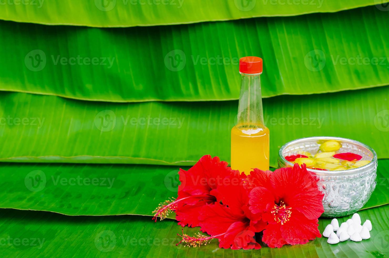 Songkran festival background with scented water, marly limestone and flowers in water bowls, for blessing on banana leaf background. photo
