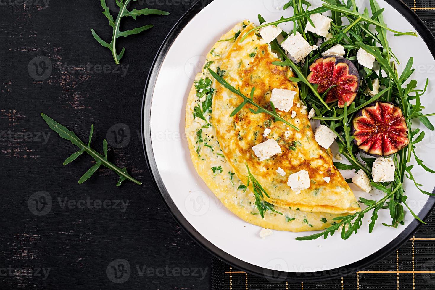 Omelette with feta cheese, parsley and salad with figs, arugula on white plate. Frittata - italian omelet. Top view. Flat lay. photo