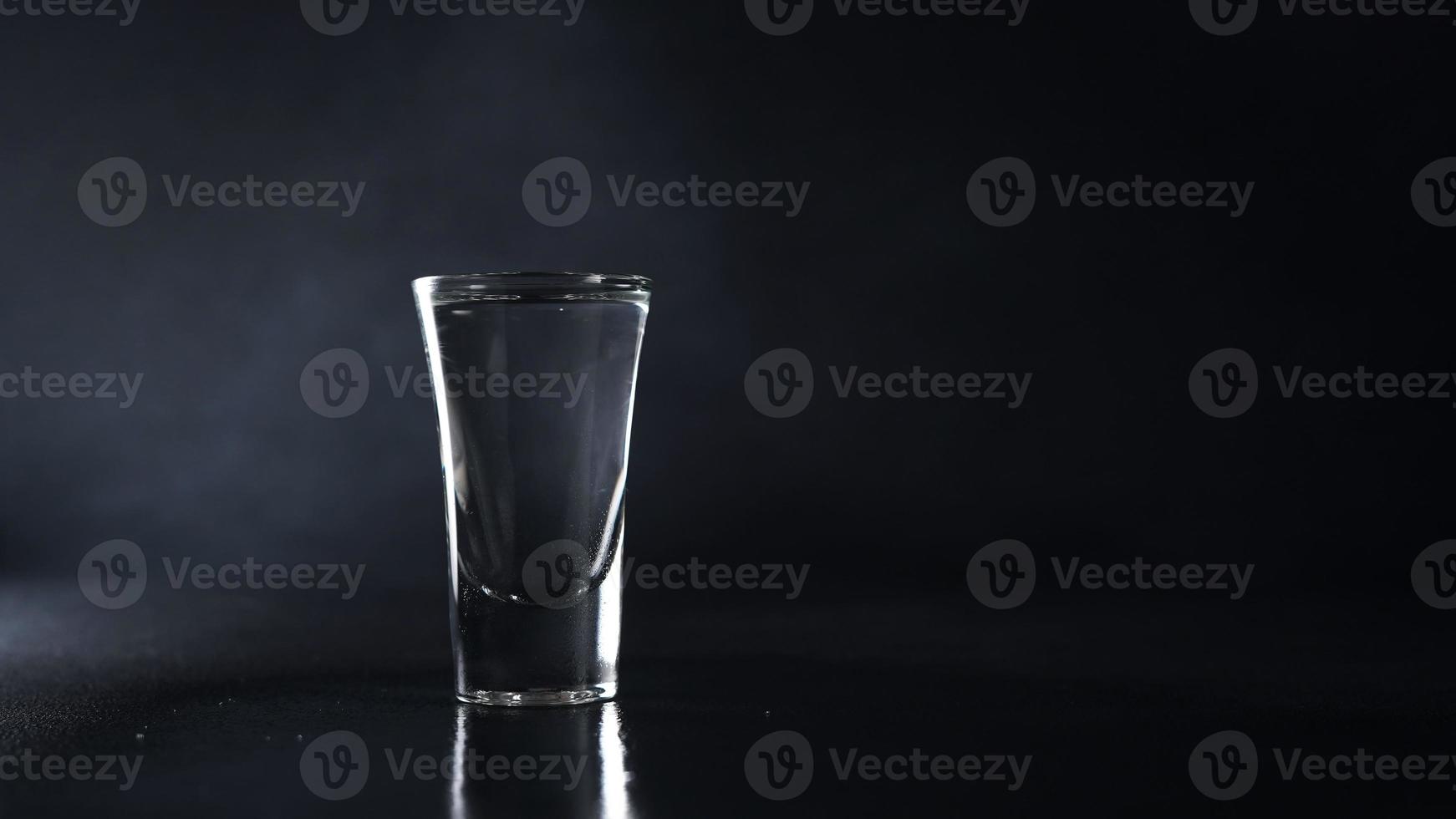 vaso de vodka en un negro antecedentes. bebida transparente vaso en un negro antecedentes. aislar. Copiar espacio foto