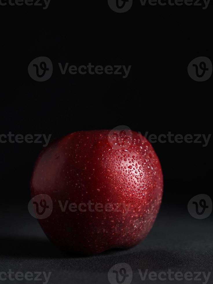 cerca arriba de rojo jugoso manzana con gotas de agua en un negro antecedentes. aislar. Copiar espacio foto