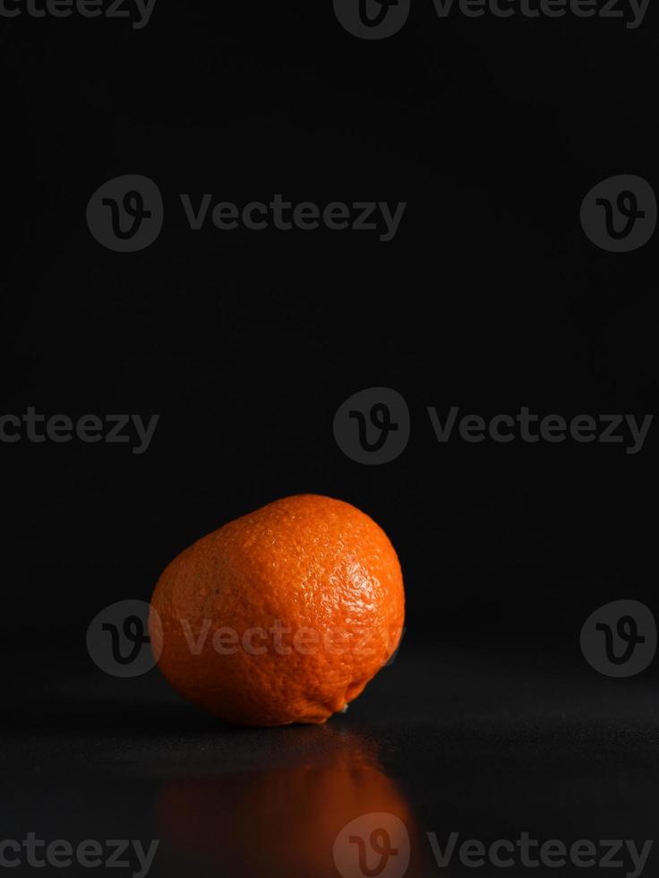 Juicy ripe Mandarin on a Black Background. Vertical shot. Isolate. Copy space photo