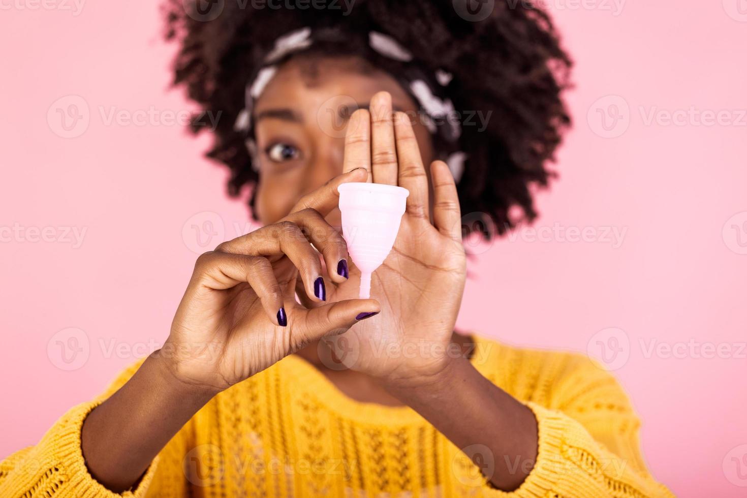 Close up portrait of African American woman holding menstrual cup isolated over purple studio background, happy female, having period, dislike to use napkins or tampons photo