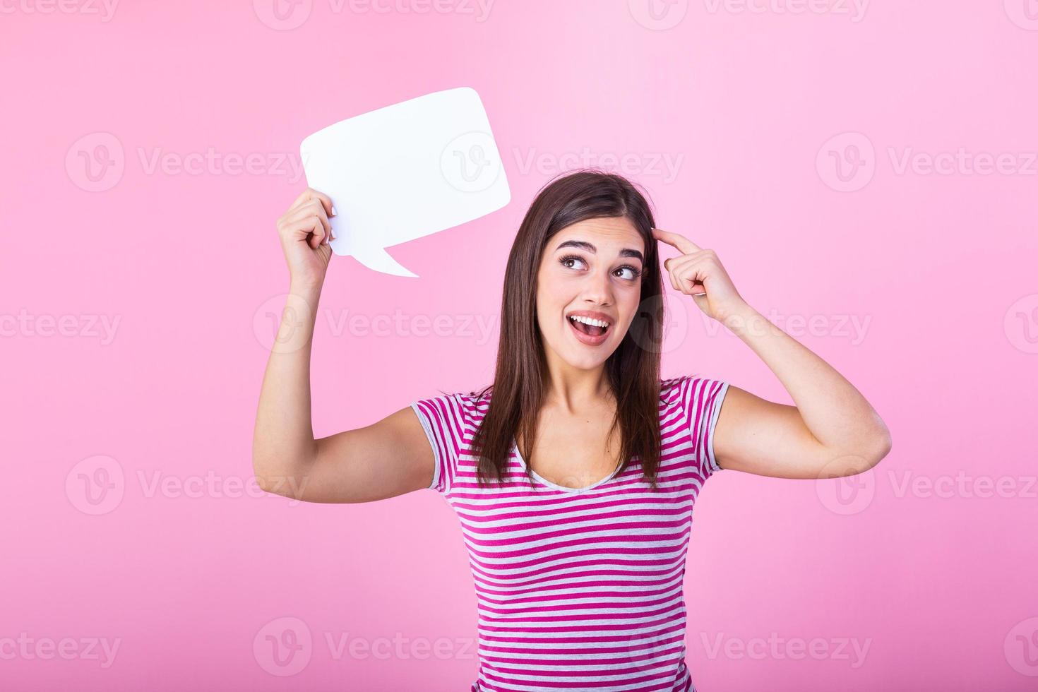 Woman showing sign speech bubble banner looking happy excited on pink background. Beautiful young joyful model on pink background having idea. photo