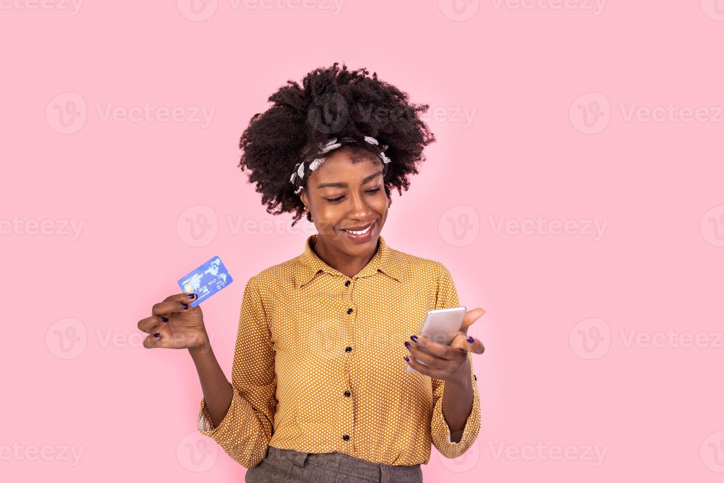 Portrait of an african woman showing credit card and mobile phone. Young woman shopping online. Beautiful woman smiling looking at camera photo