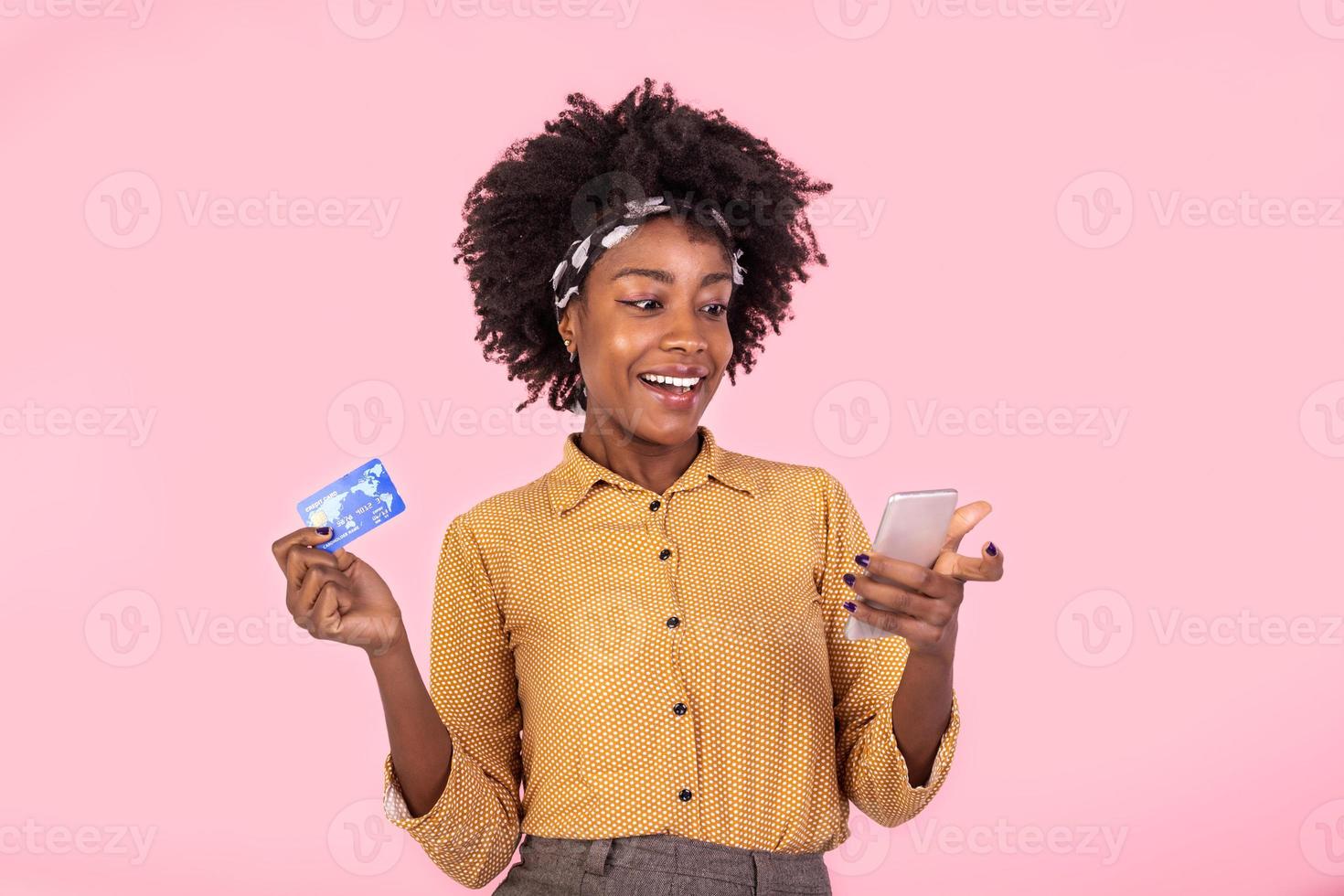 retrato de un africano americano mujer en pie en un rosado antecedentes participación teléfono inteligente y dinero, devolución de dinero. mujer participación dinero y pago en línea en su móvil teléfono foto