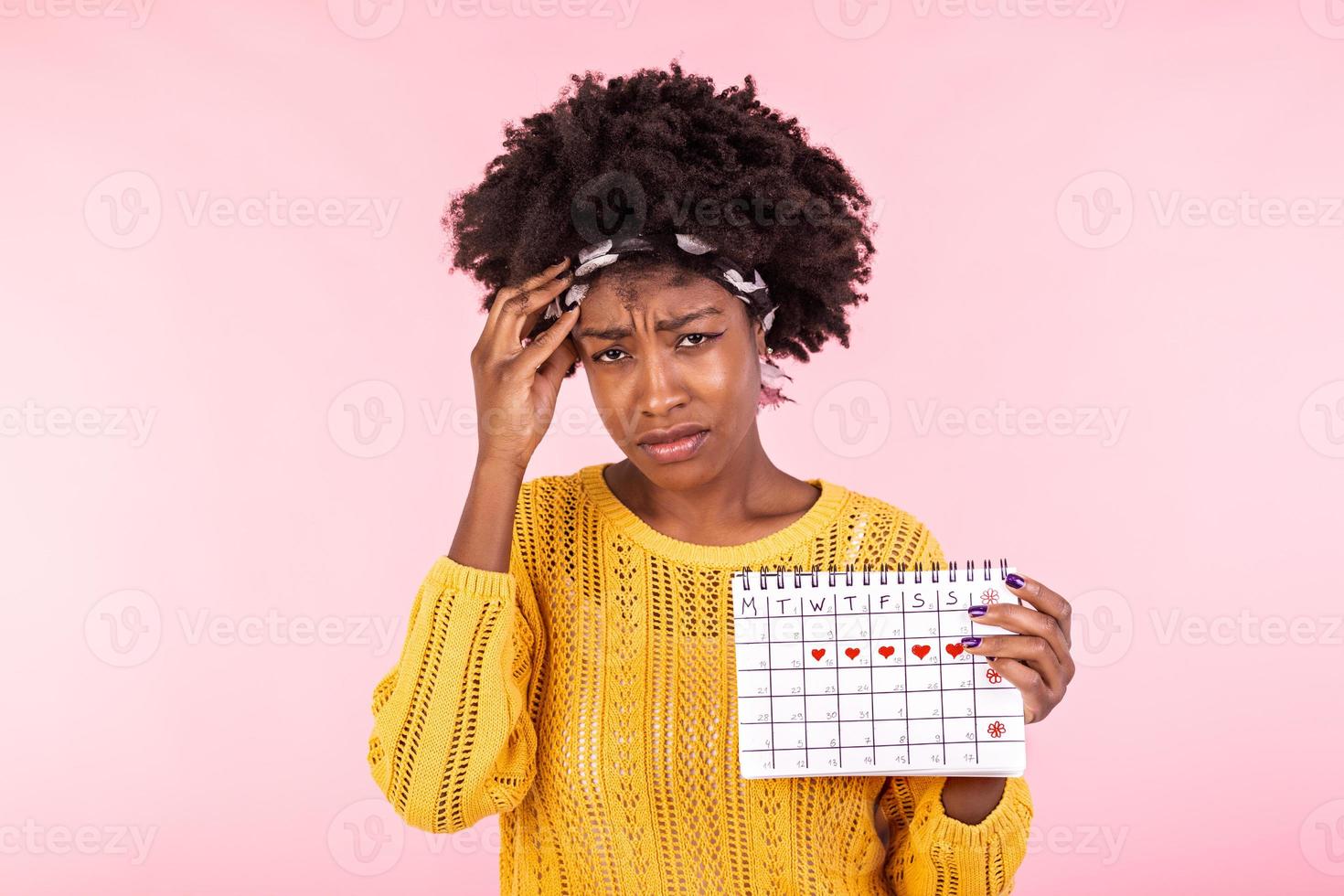 joven africano americano mujer participación menstruación calendario terminado aislado antecedentes con sorpresa rostro. mujer participación menstruación calendario con confuso rostro, temeroso y emocionado con temor expresión foto