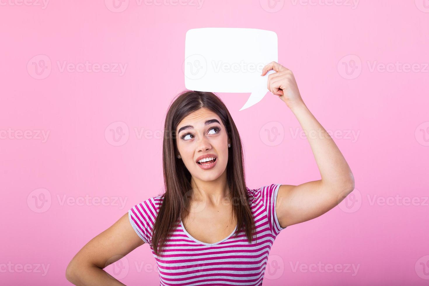 Hey, great idea. Happy pensive beautiful girl looking at blank speech bubble, copy space. Beautiful young joyful model on pink background having idea. photo