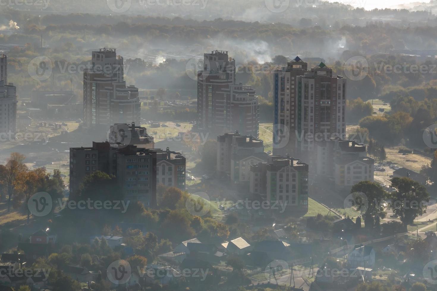 aerial view of green city with skysrapers and residential buildings in earning fog and mist photo