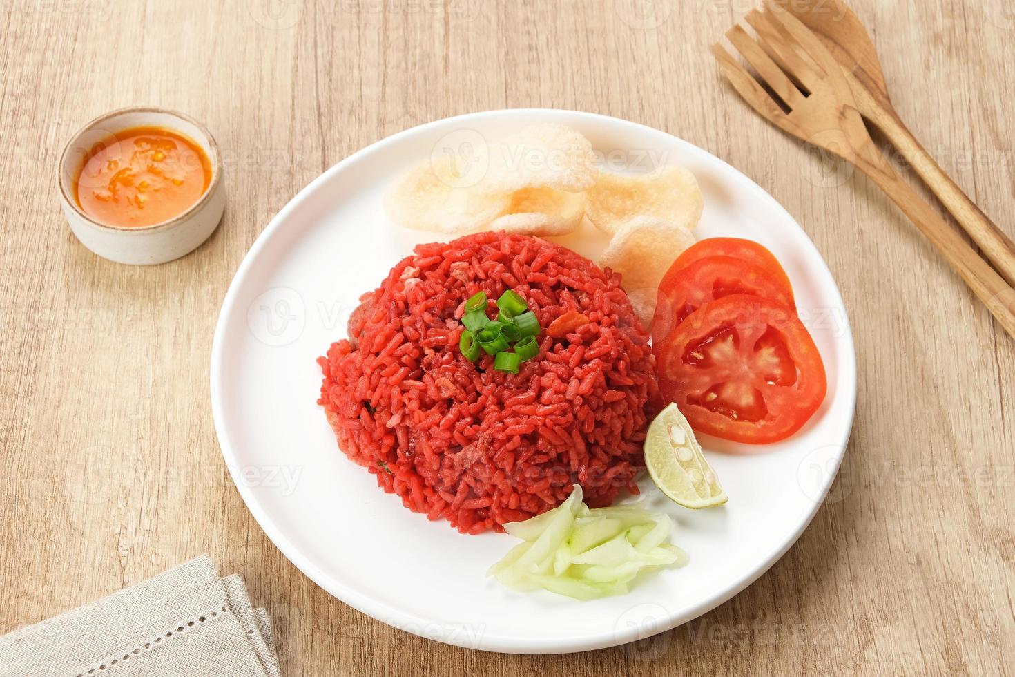 Nasi Goreng Merah, traditional food from Makassar, Indonesia. Fried rice with tomato sauce, shrimp, meatballs and egg. Served with pickled cucumber, chili sauce and lime photo