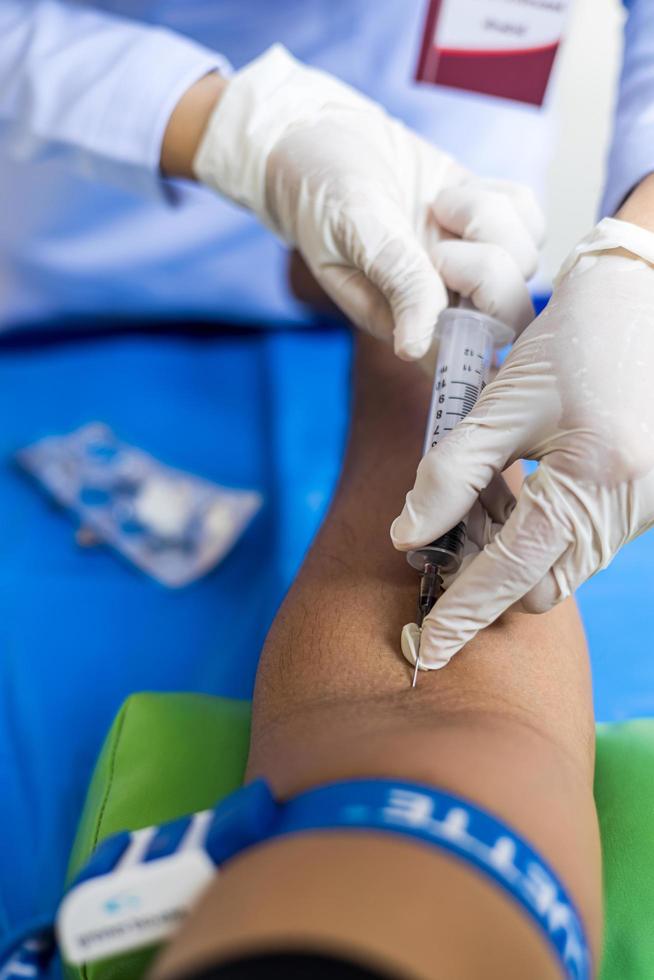 Close-up view, a nurse wearing white latex gloves is using a syringe to puncture a major artery. photo