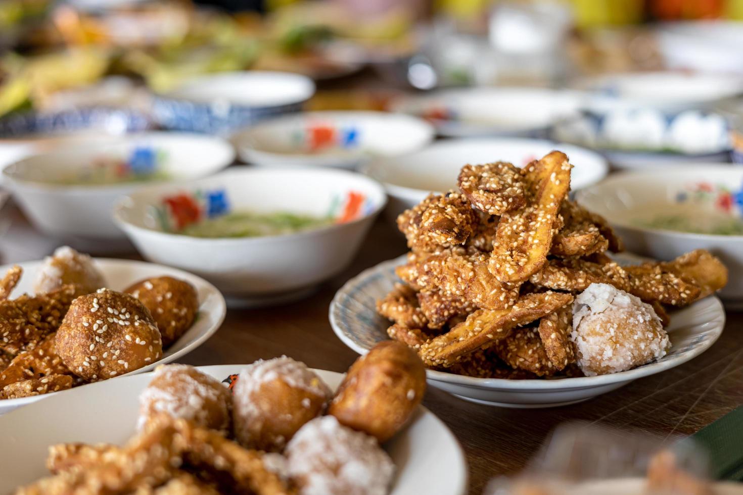 Many delicious fried banana snacks packed in plates placed amongst other Thai desserts. photo