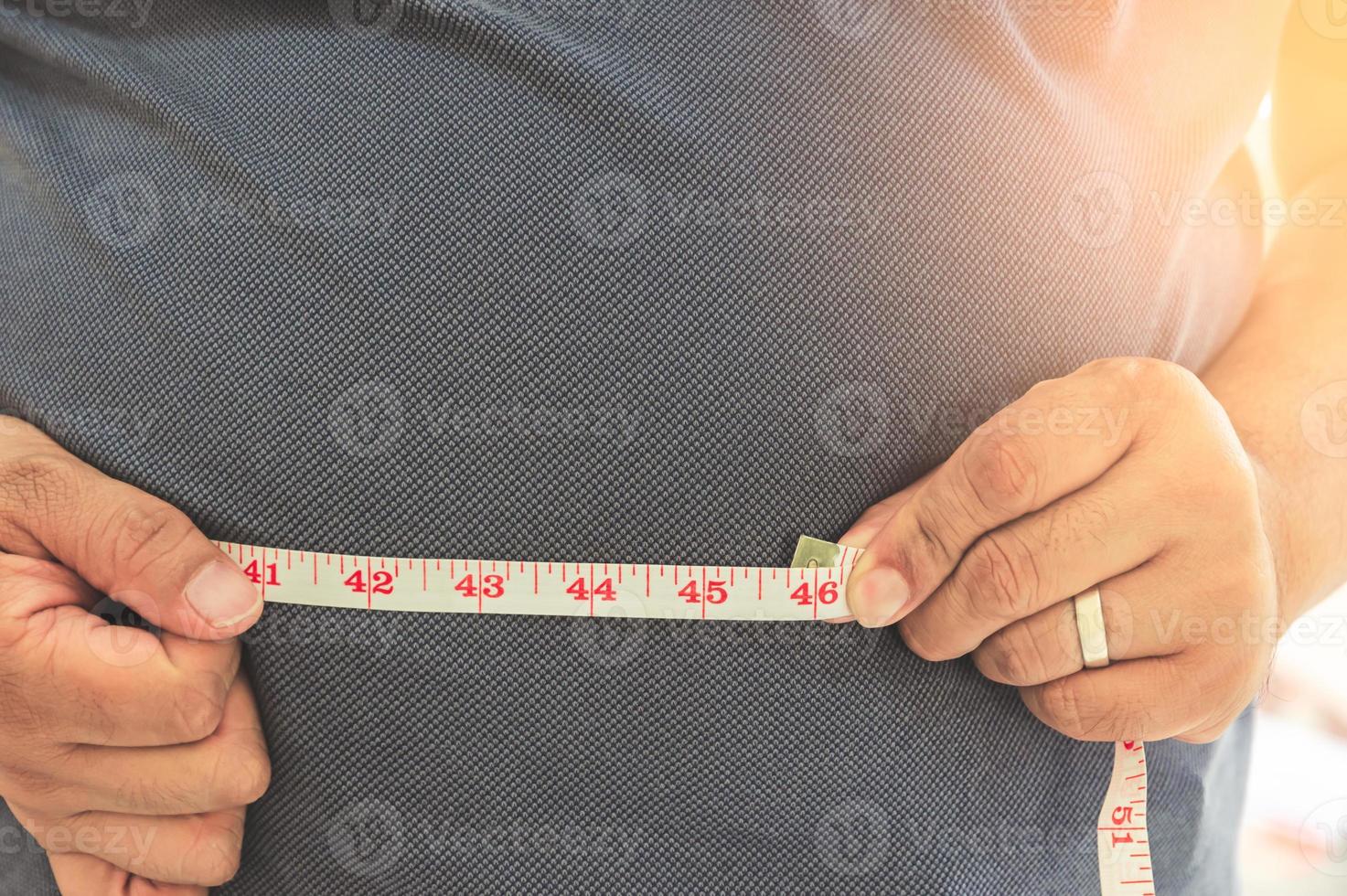 Fat mature man measuring his belly with measurement tape. Obesity and weight loss concept photo