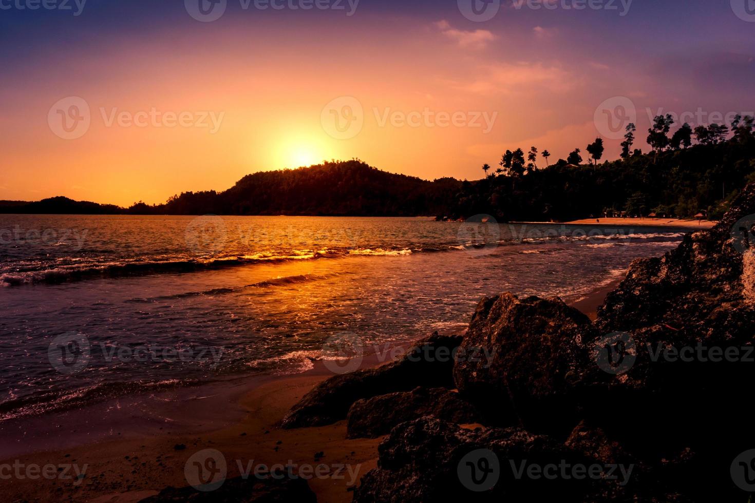 Sunset over a hill at beach. Dramatic seaside landscape with hill and rocks photo