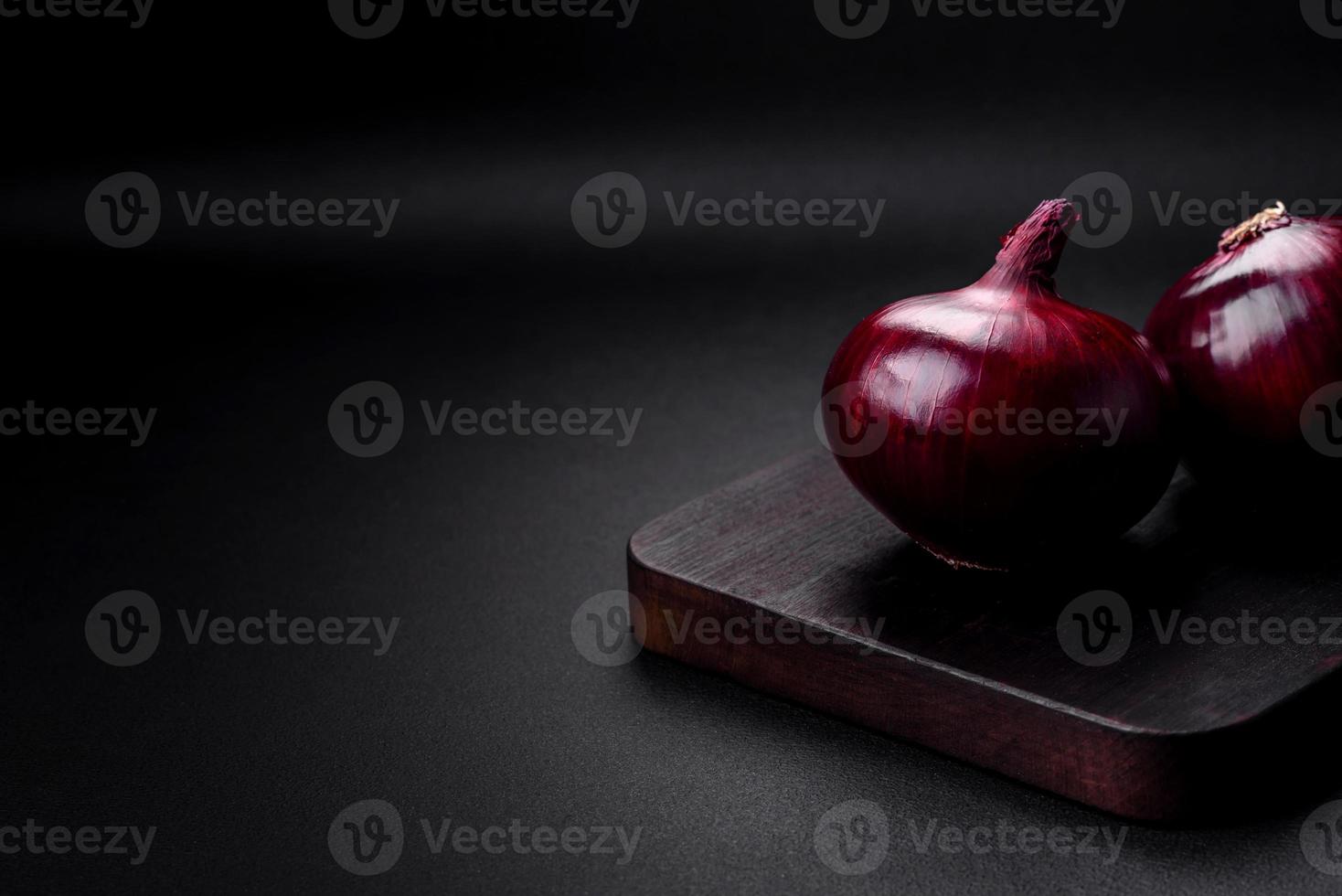 Fresh raw red onion on dark textured concrete background photo