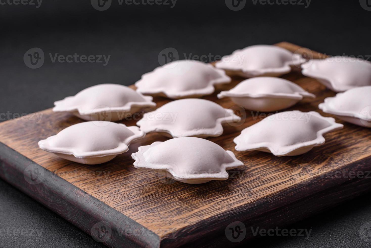 Raw frozen stuffed dumplings on a wooden cutting board photo