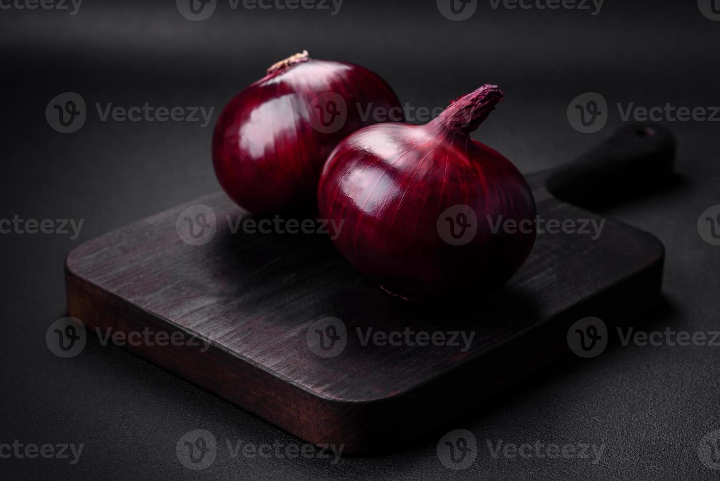 Fresh raw red onion on dark textured concrete background photo