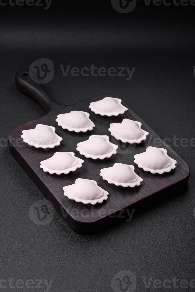 Raw frozen stuffed dumplings on a wooden cutting board photo