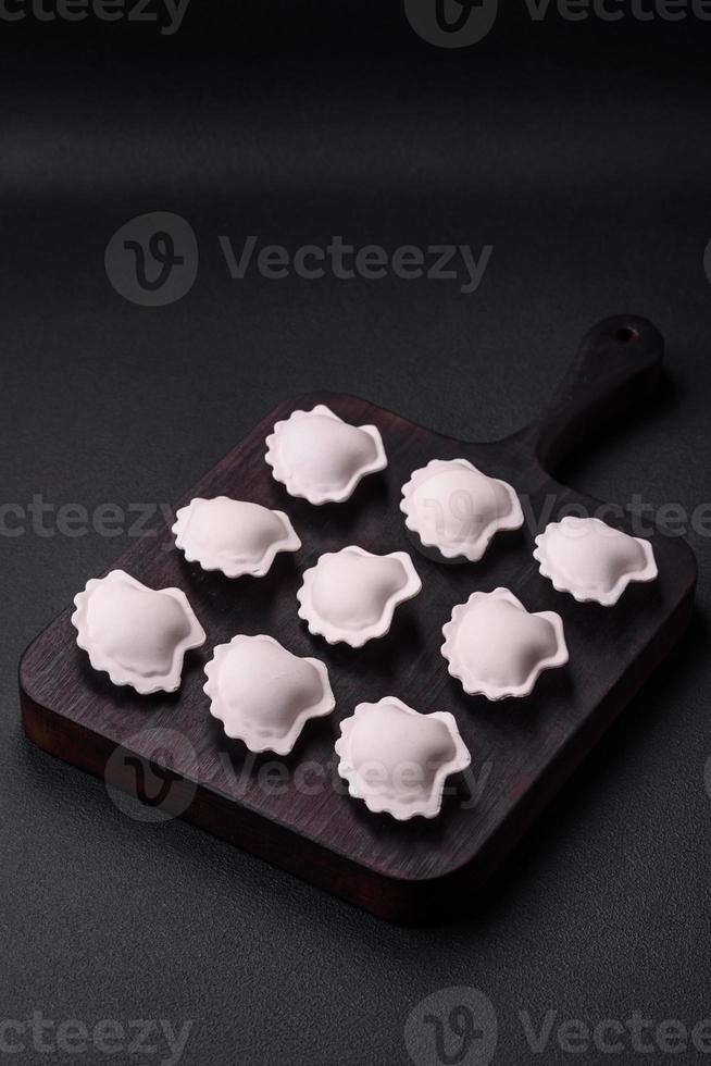 Raw frozen stuffed dumplings on a wooden cutting board photo