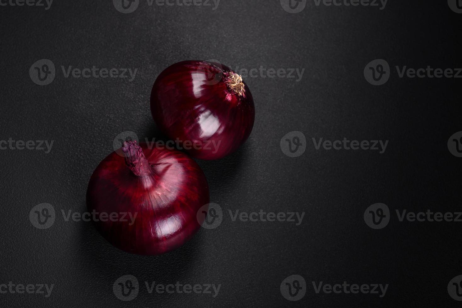 Fresh raw red onion on dark textured concrete background photo