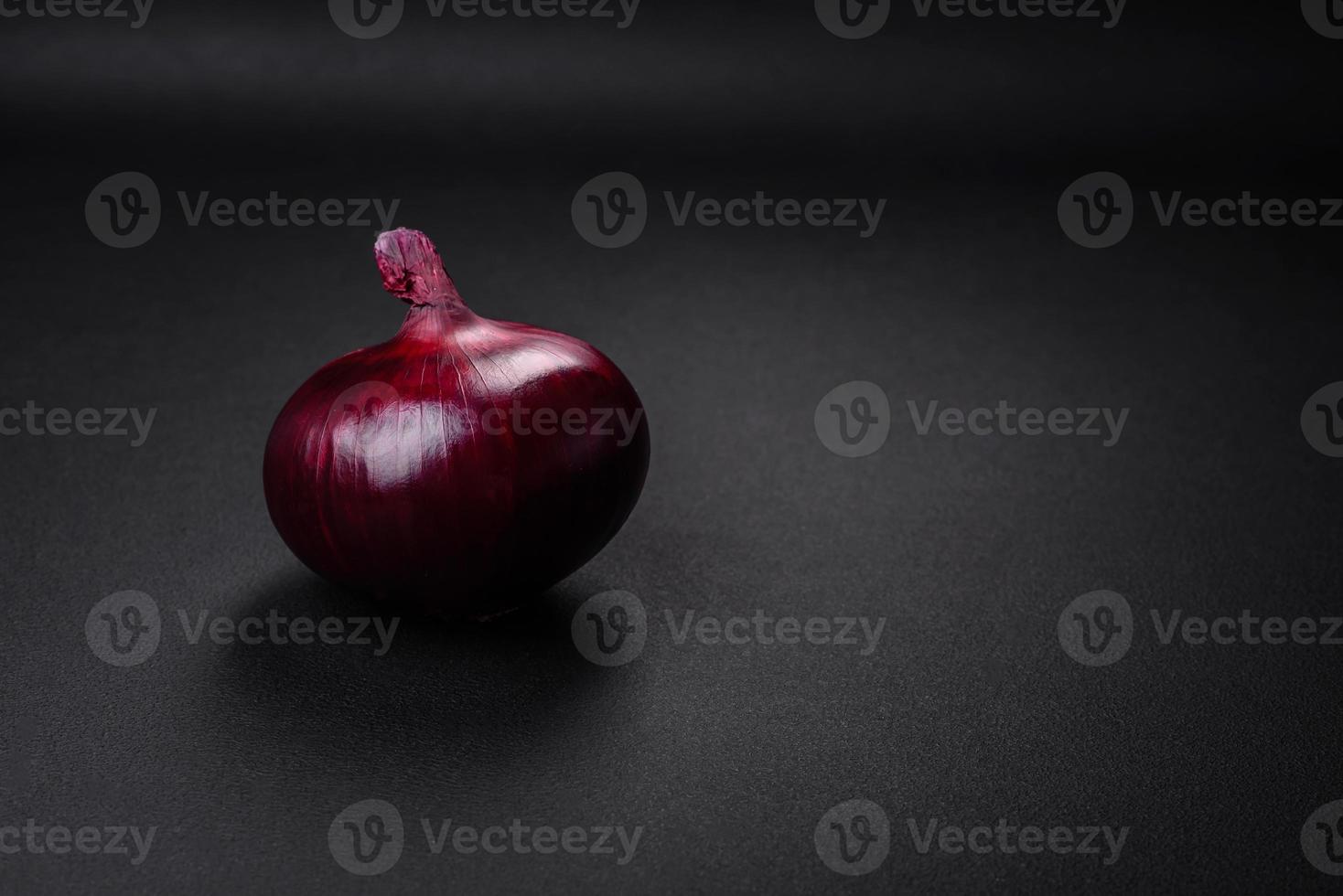 Fresh raw red onion on dark textured concrete background photo