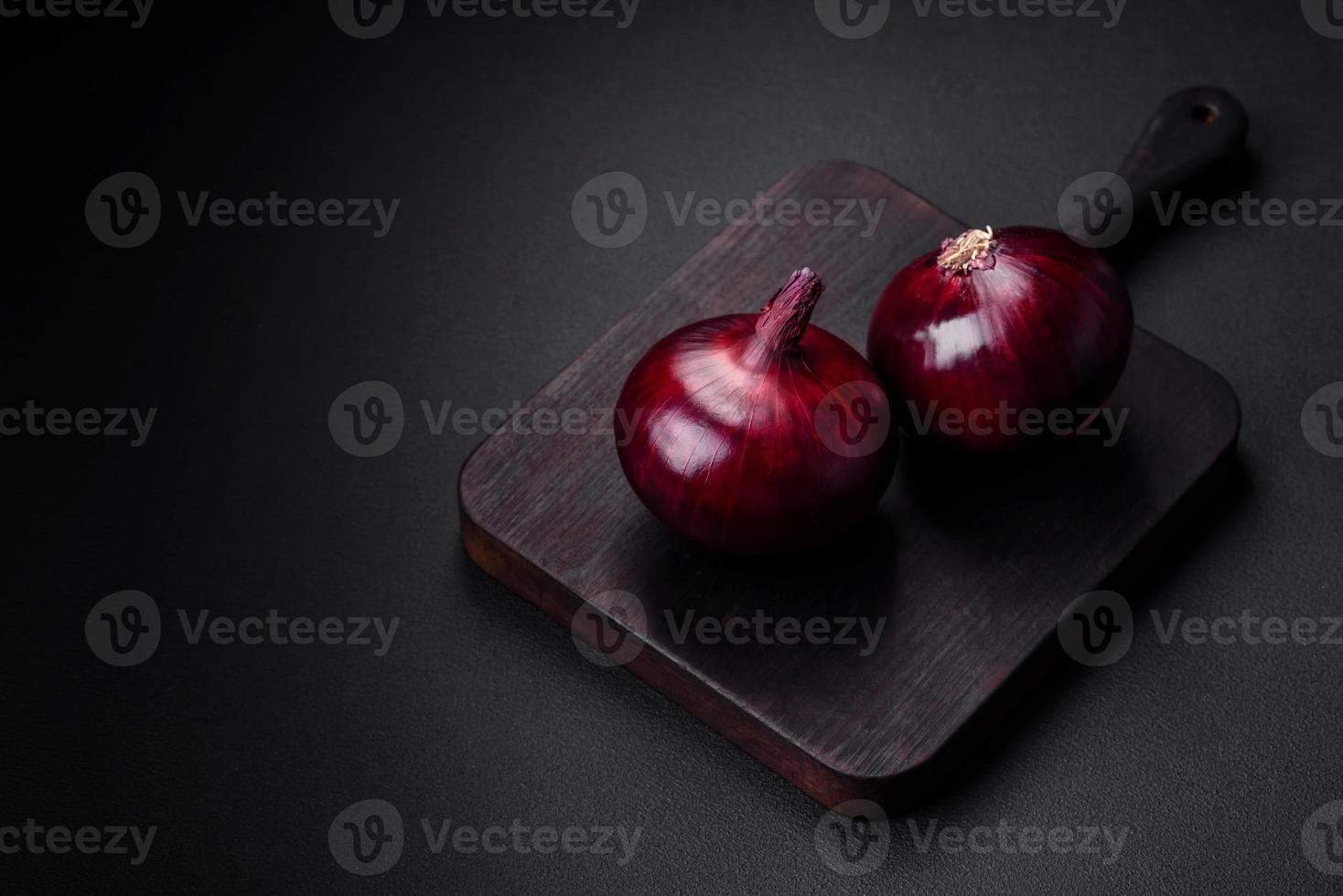 Fresh raw red onion on dark textured concrete background photo