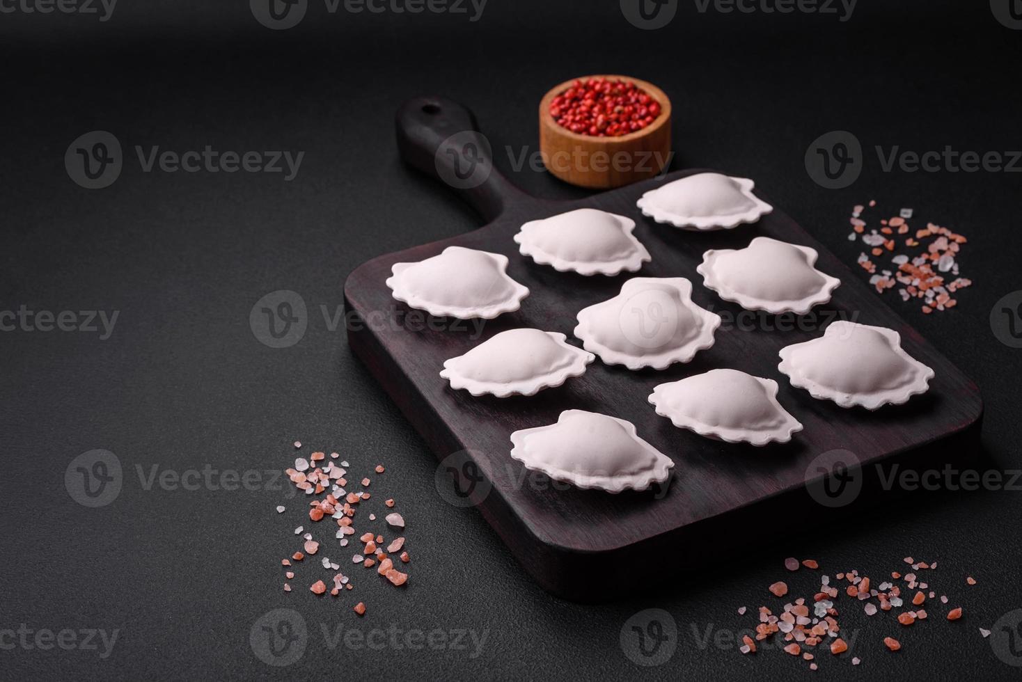 Raw frozen stuffed dumplings on a wooden cutting board photo